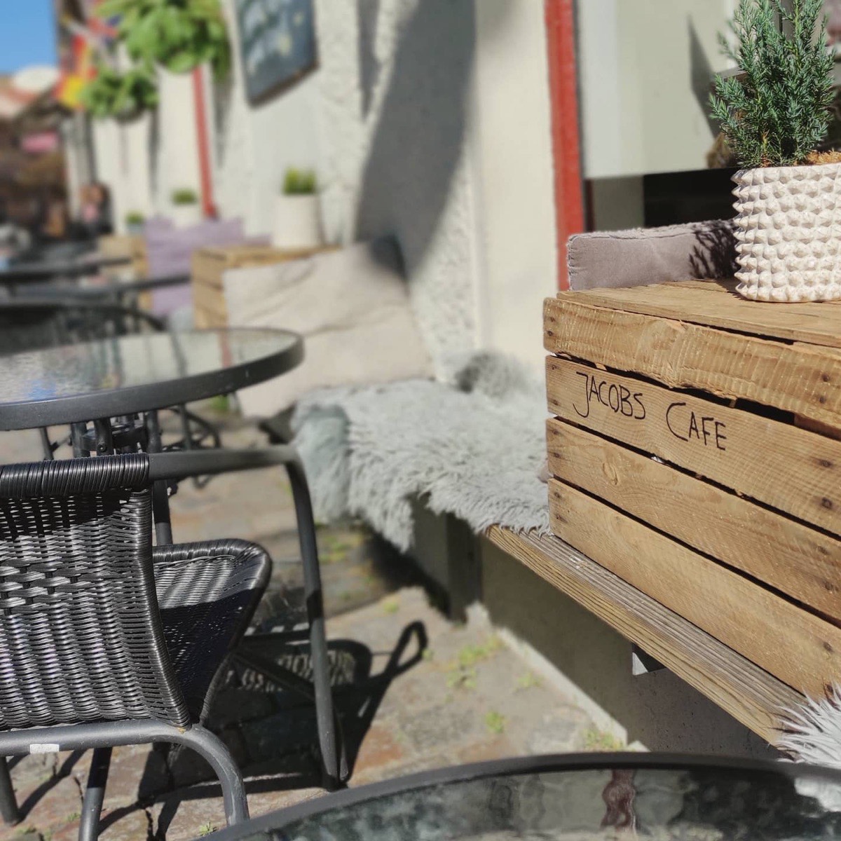 Bänken utanför kaféet med fårskinn och en trälåda med texten Jacob's Café