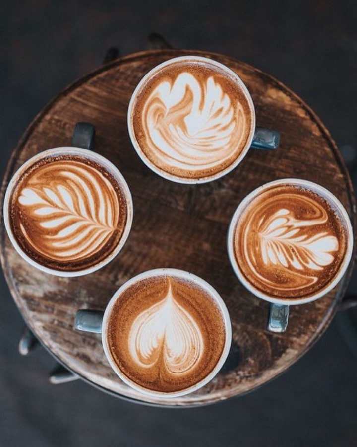 Fyra caffè latte med latte art på en bricka